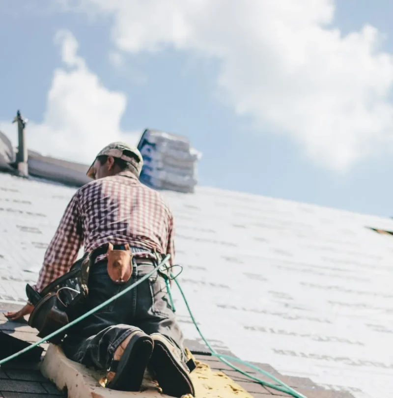 Roofer adding shingles to the roof of a house